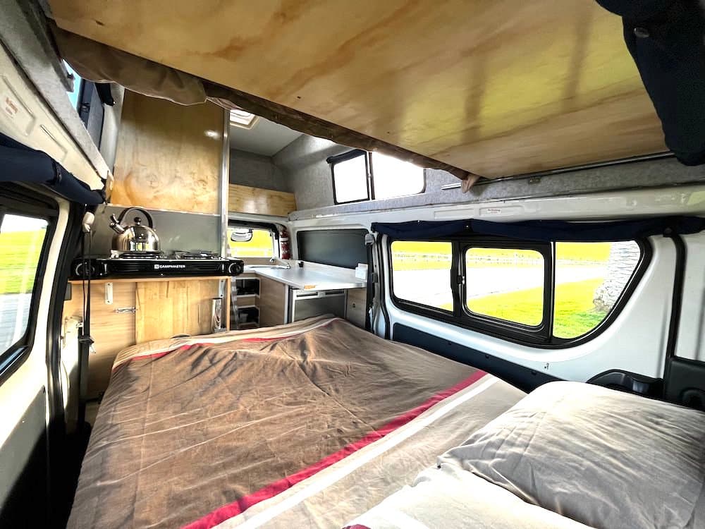 Both campervan beds made up, the lower double across the floor and the over-cab double above