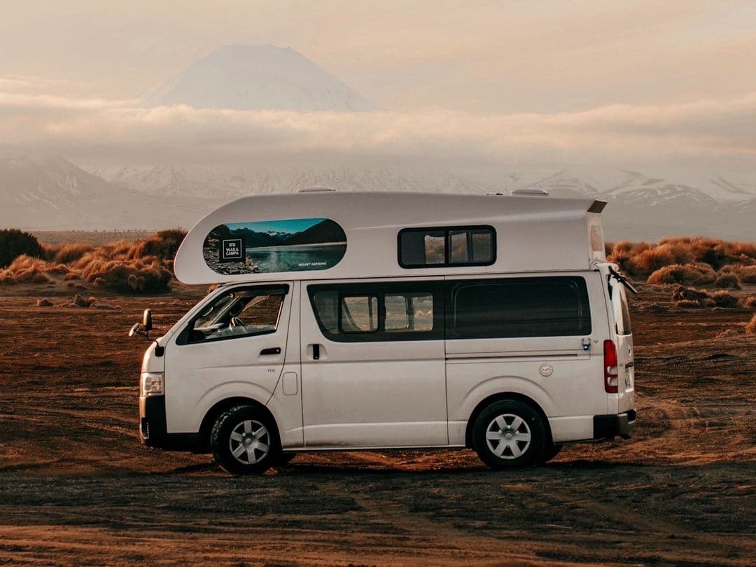Side profile of the campervan parked on gravel with a volcanic cone behind
