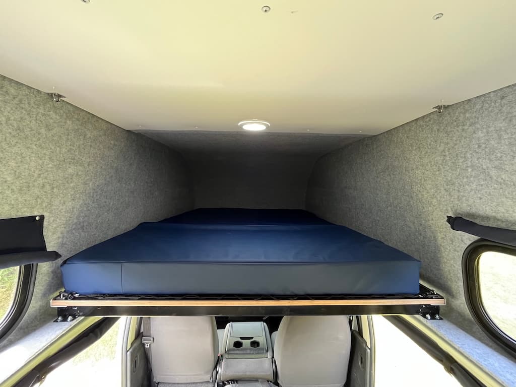 Double mattress on a frame inside the fibreglass pod above the cab seats